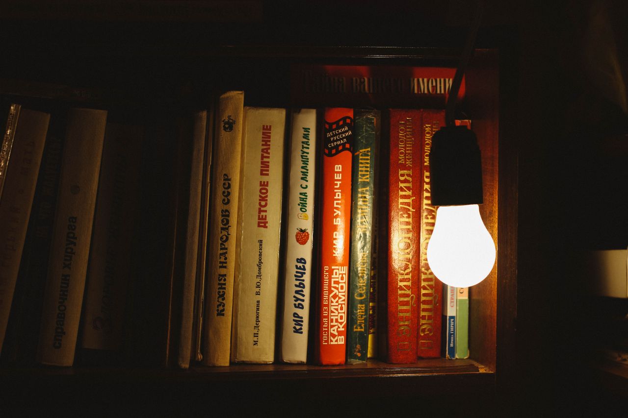 Books on a shelf illuminated by a single light bulb, creating a warm atmosphere.