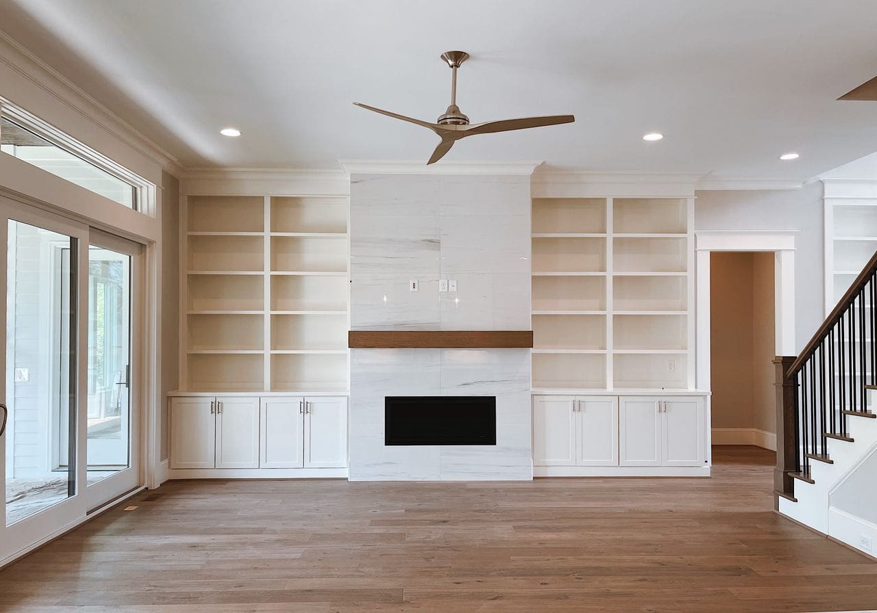 Home Contemporary living room with built-in shelves, fireplace, and ceiling fan.